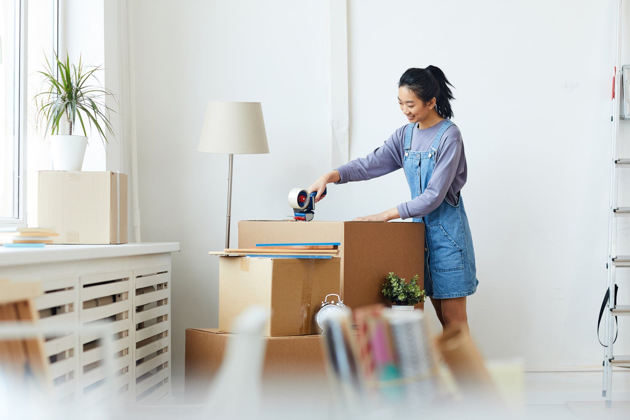 A woman tapes a cardboard box shut after packing it.