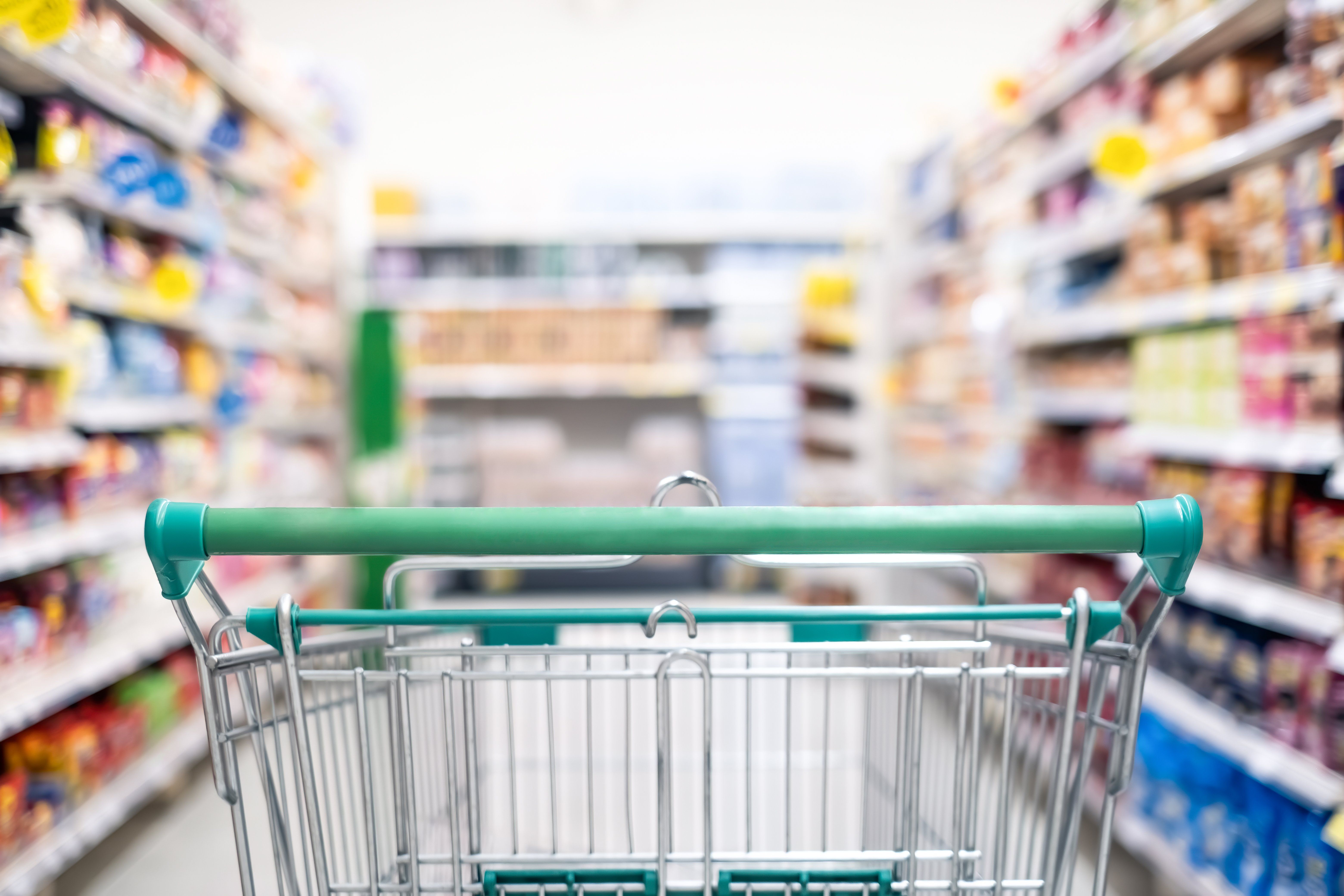 A shopping cart sitting in a grocer store aisle.