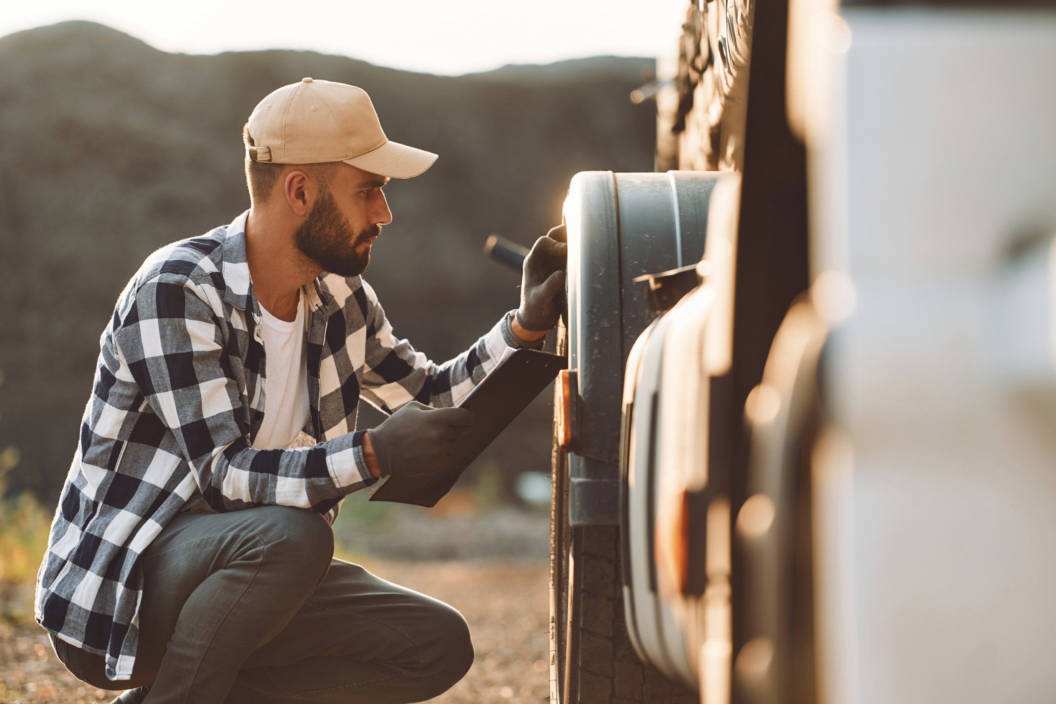 A truck driver inspects the front tires of his truck.