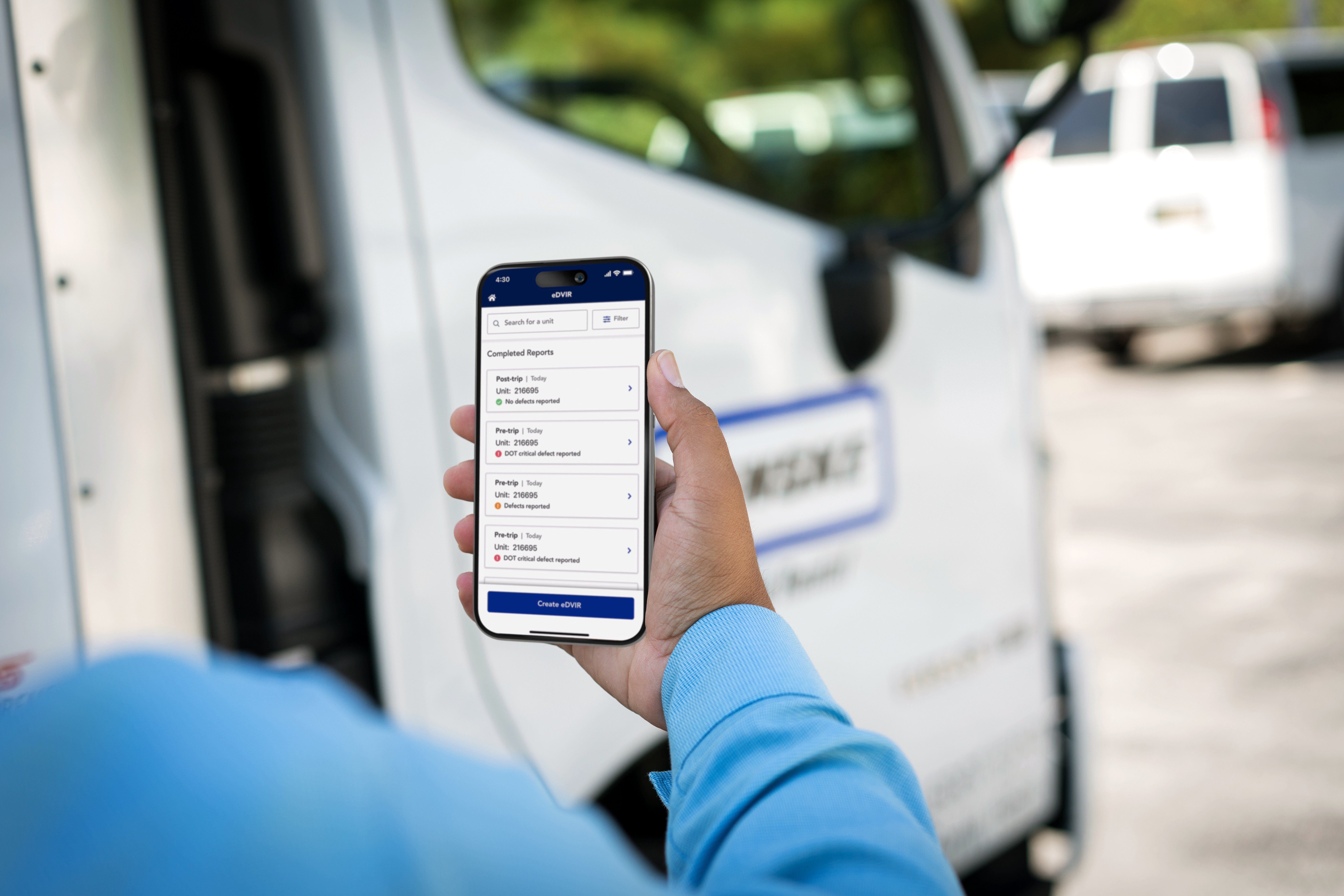 A person holds a smartphone displaying the Penske Driver mobile app's eDVIR feature. In the background, a Penske truck is visible suggesting the context of vehicle inspections.