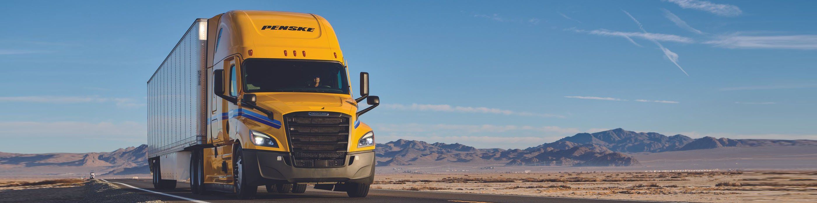Yellow Penske truck driving in the desert