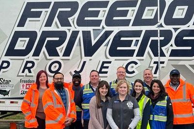 Leaders from Penske Logistics pose with Truckers Against Trafficking associates outside of the Freedom Driver Project Trailer.